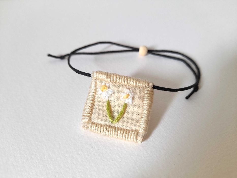 Pulseira bordada à mão com pingente de margarida branca