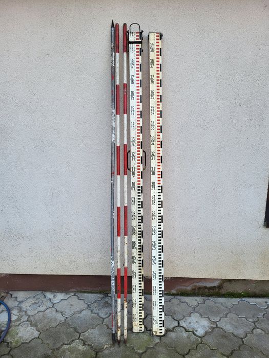 Stara łata niwelacyjna i trzy tyczki.