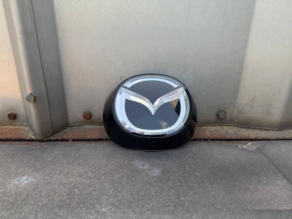 Эмблема решетки радиатора с подиумом  Mazda CX-5 17-21
