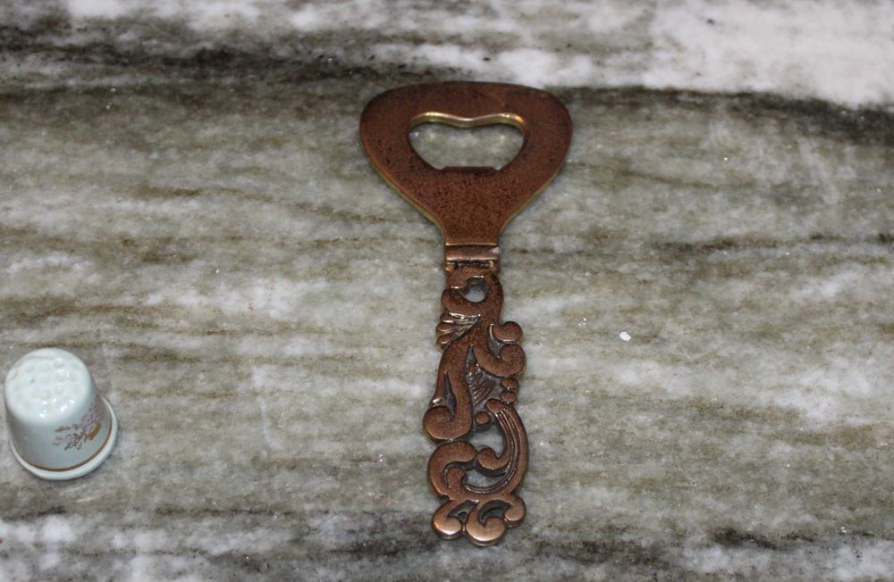 Um grande abridor antigo de garrafas de latão com relevo, anos 60.