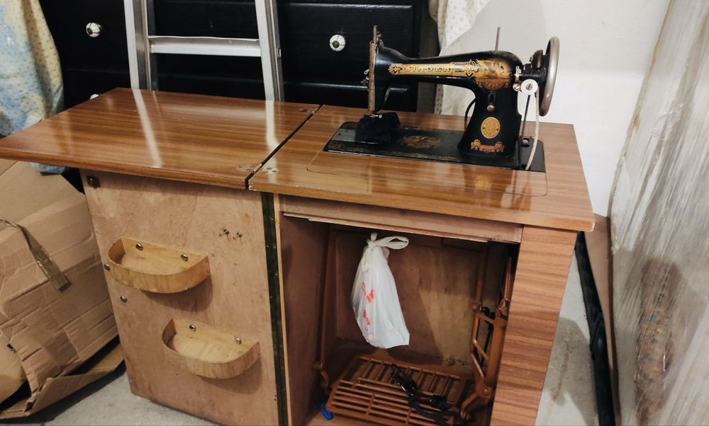 máquina de costura Singer antiga em móvel com pedal - icónico decalque dourado “Sphinx”