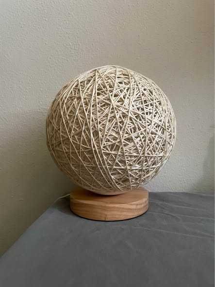 Candeeiro de mesa com esfera em fibra natural e base em madeira