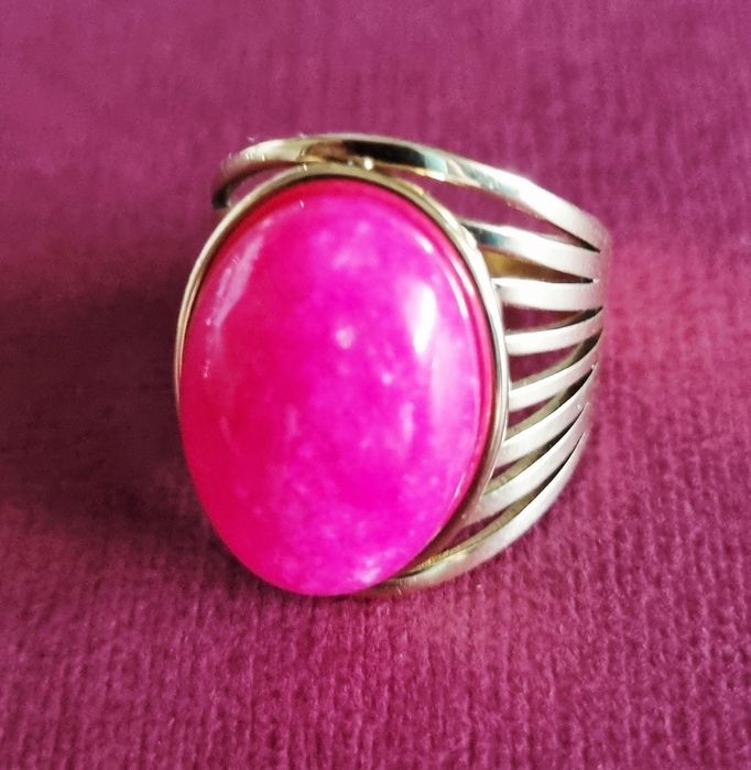 Anel dourado, em aço, com pedra oval rosa fucsia. 18/ajustável