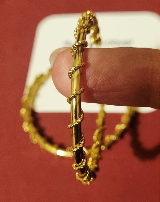 Brincos/argolas douradas, em aço, com cerca de 5cm de comprimento.