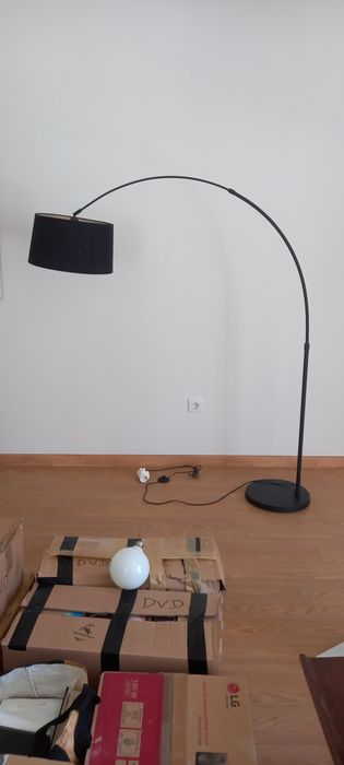 Candeeiro alto curvo, com base em metal preto.