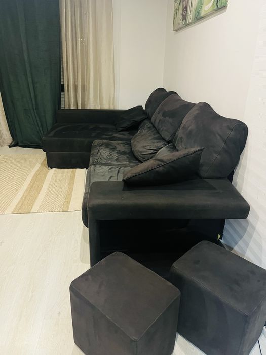 Sofá preto chaise longue, com arrumacão e 2 bancos