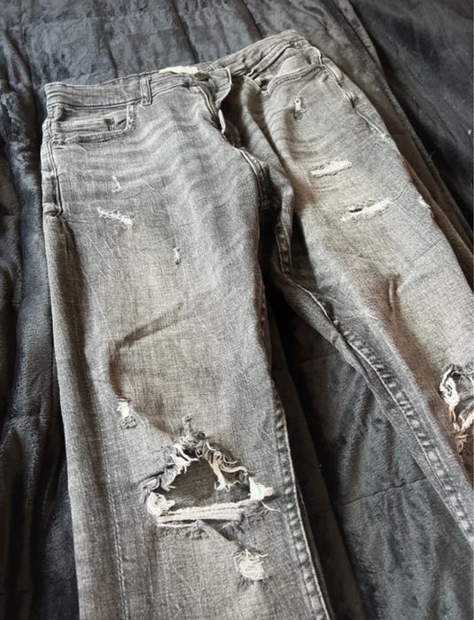 Calças de ganga cinza escura, com detalhes de rasgos