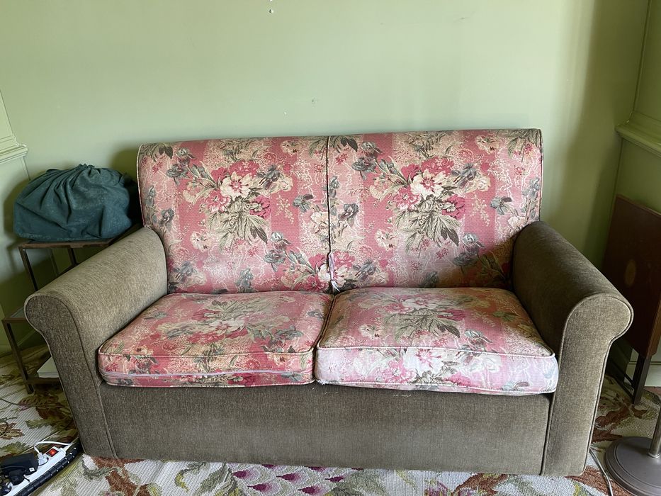 Sofa de 2 lugares em verde e com padrao de flores rosa.