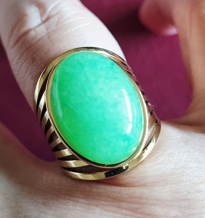Anel dourado, em aço, com pedra oval verde claro. 18/ajustável