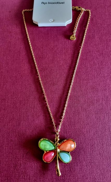 Colar dourado, em aço, com libelinha colorida. Tem extensor