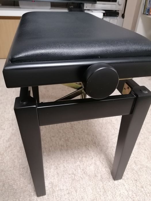 Banco de piano com assento e pele preta.