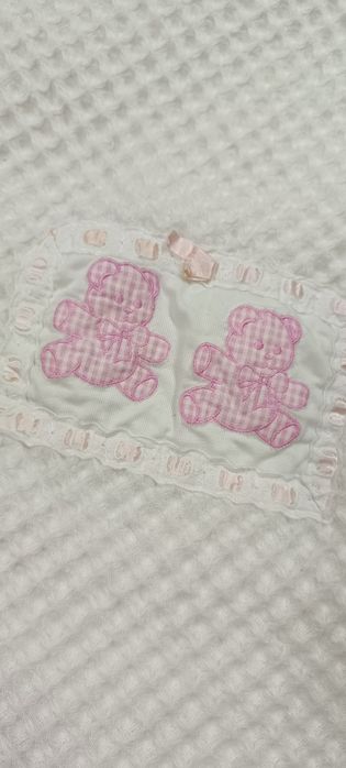 Manta de criança branca com folho e bonecos em cor de rosa . Tem umas