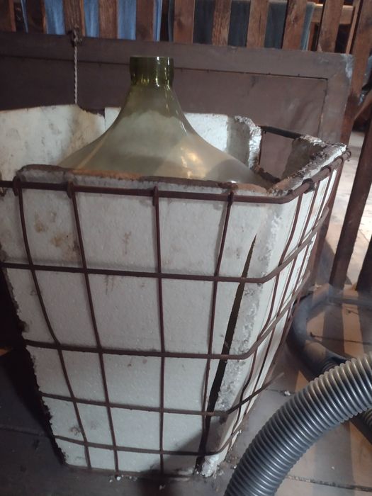 Duży balon gąsior na wino w koszu metalowym ze styropianem