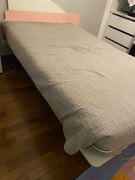 Cama em tons rosa e branco com suporte lateral