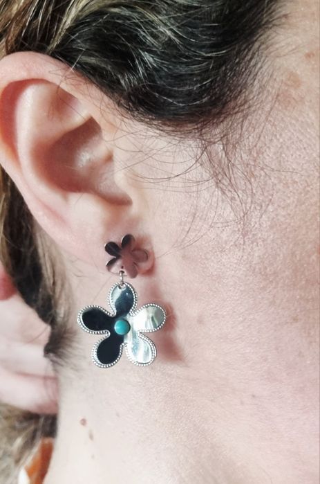 Brincos prateados, em aço, 2 flores de diferentes tamanhos com 1 pedrinha turquesa.