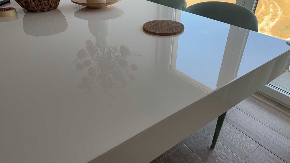 Mesa de jantar branca com acabamento em esmalte cozido e quatro cadeiras em tecido