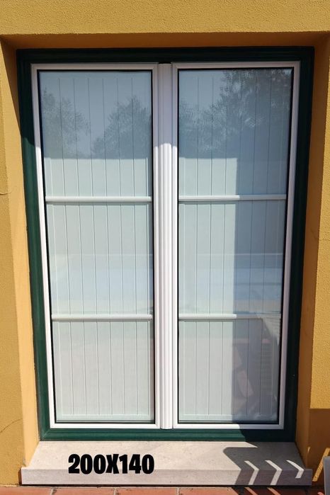 Janelas em alumínio, brancas e verdes, com veda luz interior.