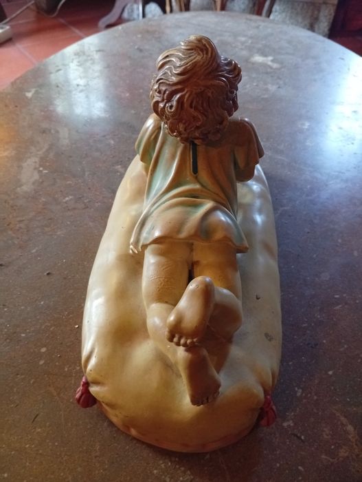 Figura cerâmica de bebé sobre uma almofada com uma bola