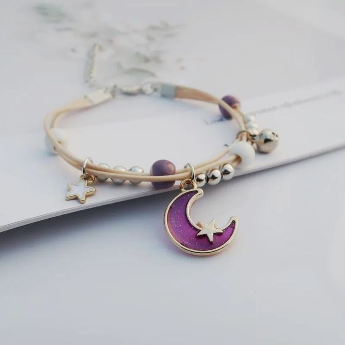 Pulseira/tornozeleira luas em tons de lilás, azul e rosa.