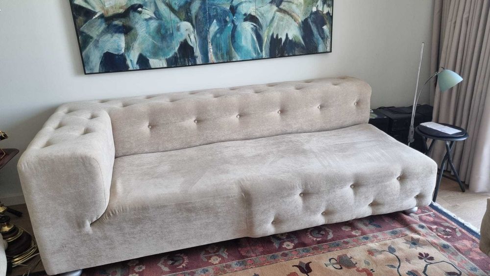 Sofá estofado em tecido bege estilo Chesterfield