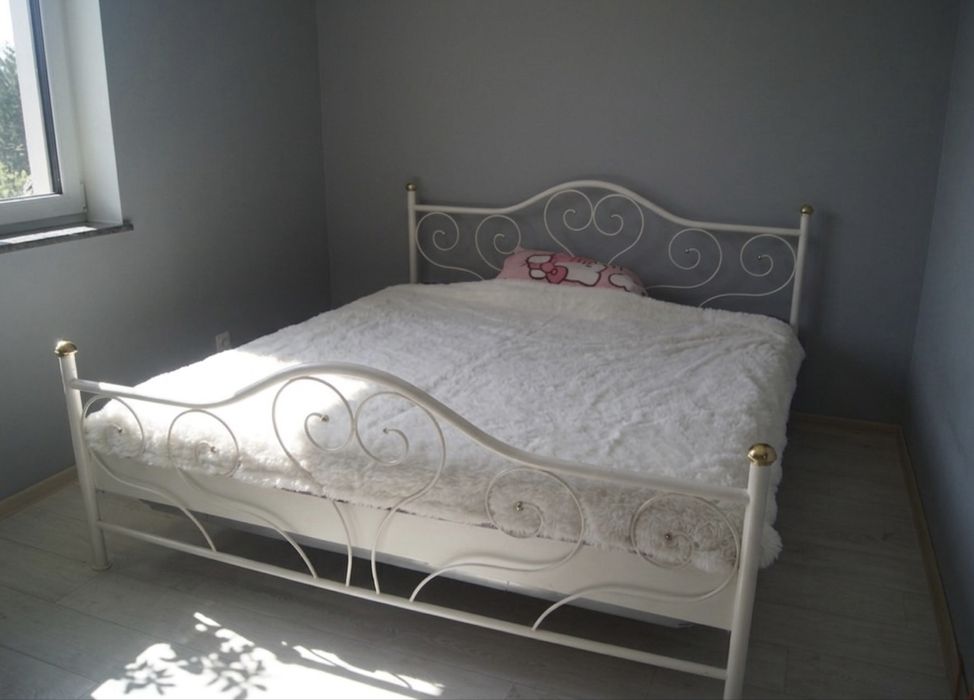 Białe łóżko ze złotymi elementami