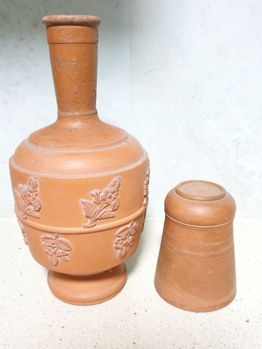 Antiga garrafa de água com copo em barro