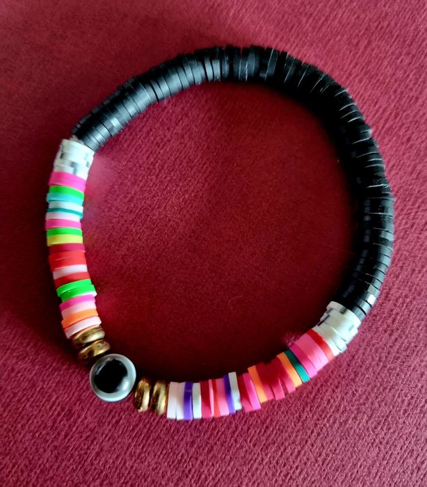 Pulseira elástica em tons de preto e multicor. Com olho de proteção