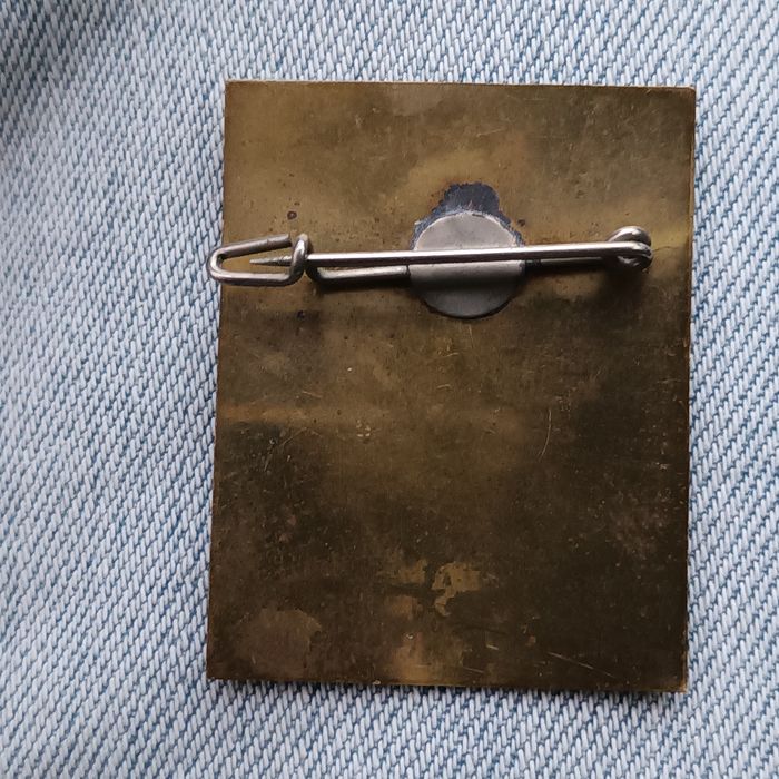 Trata-se de um alfinete de lapela ou emblema comemorativo do acampamen