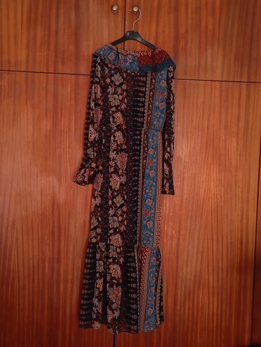 Vestido longo de tons escuros.