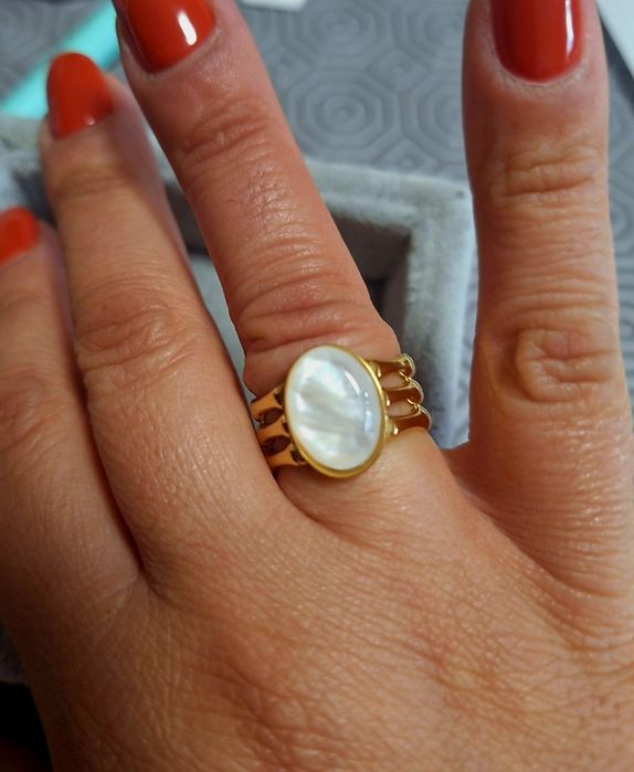 Anel dourado, em aço, com uma madrepérola oval.  Ajustável