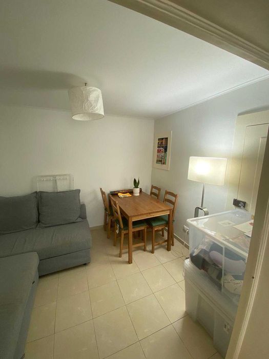 sofá grande, duas cadeiras, caixas de arrumação e livros