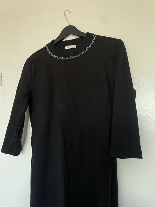 Dzianinowa sukienka z ozdobą przy dekolcie.