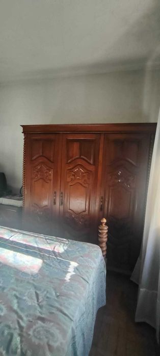 Quarto em madeira maciça, duas mesinhas de cabeceira, um armário e duas cadeiras.