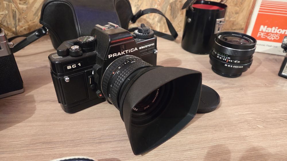Praktica - aparat analogowy i akcesoria: lampa błyskowa, filtr, redukcja, oryginalny nowy pasek. Zestaw