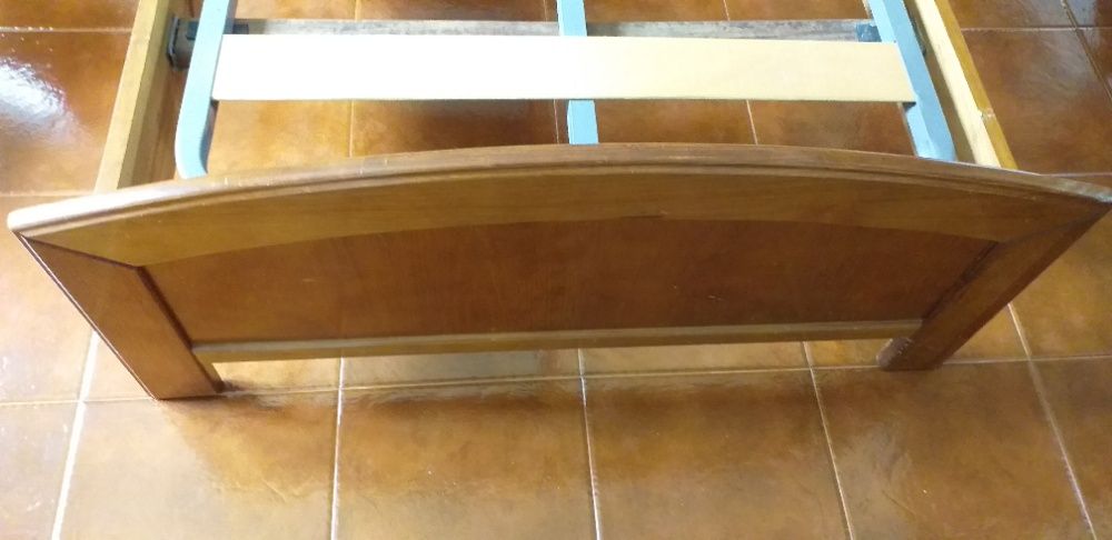 Cama de solteiro com estrado e mesa de cabeceira.