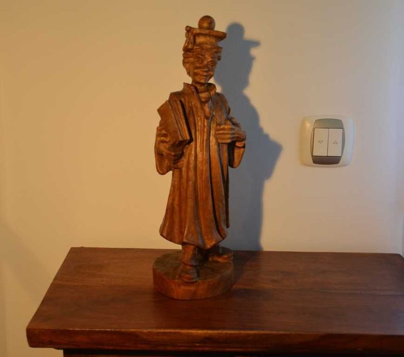 Estatueta esculpida em madeira maciça, representando um estudante universitário