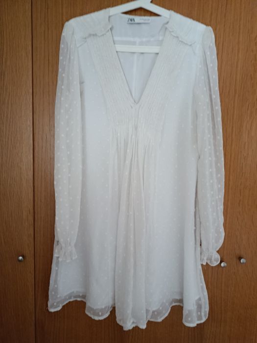 Vestido branco decote em V
Camada exterior com detalhes e folhos
Forro