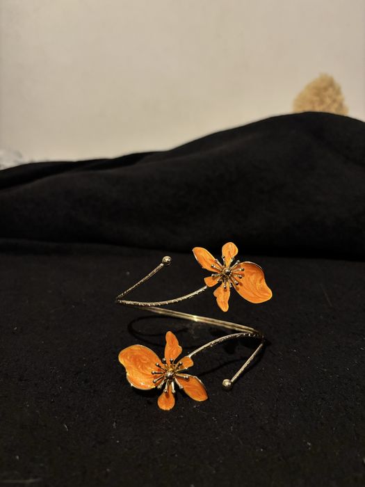 Pulseira de braço dourada com flores laranjs