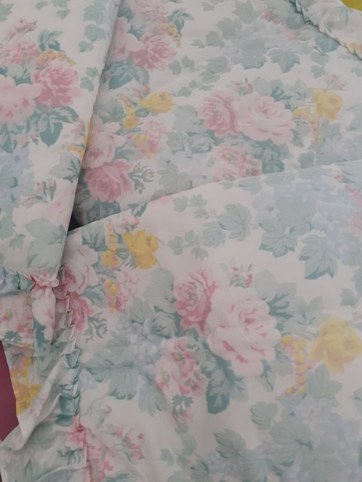 Colcha almofadada com folhos laterais e ao fundo.