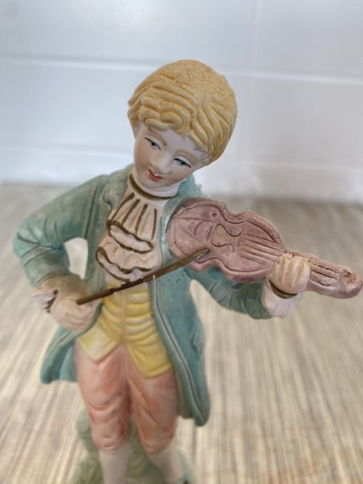 Estátua em cerâmica de um homem que segura um violino