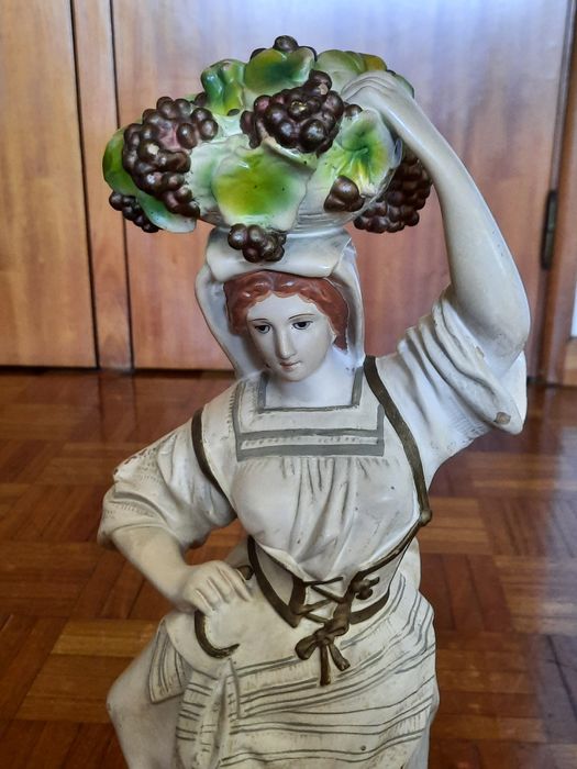 Estatueta decorativa em porcelana - camponesa com cesto de uvas