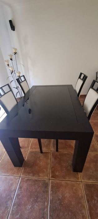 Mesa de jantar extensível em carvalho escuro com tapo de vidro preto.