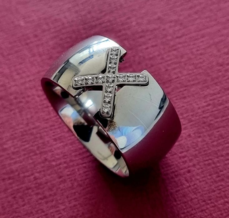 Anel grosso prateado, em aço, com um X em zirconias. T20