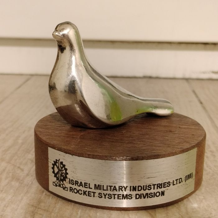 srebrna figurka ptaka (symbolu pokoju) na drewnianym stojaku