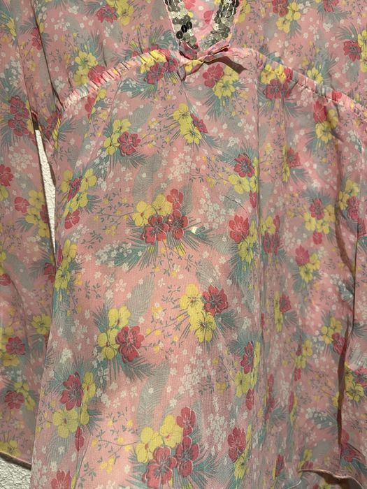 Różowa bluzka z kwiatowym nadrukiem i cekinami.