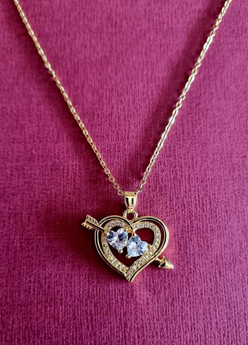 Colar dourado, em aço, com 2 corações unidos por uma flecha.