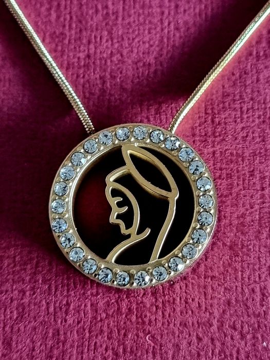 Colar dourado, em aço, com pingente da Nossa Senhora rodeada de zirconias.