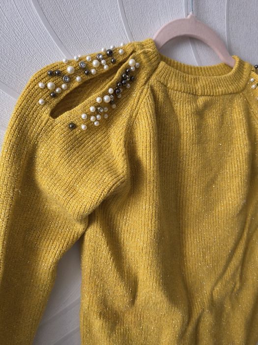 Кофта жовтого кольору з вирізами на плечах, які оздоблені паєтками