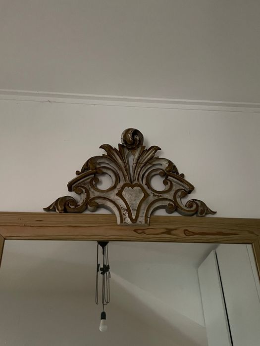 espelho antigo com moldura de madeira e frontão entalhado decorativo.