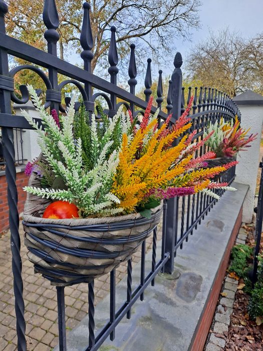 Wrzosy sztuczne w koszyku na ogrodzenie.